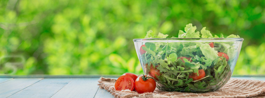 A salad in a bowl on a table in a forest setting